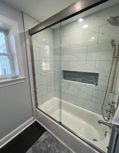 New bathtub with a large horizontal, mitered tile niche by MM Home Improvements in Berwyn, featuring vein-matched tile.